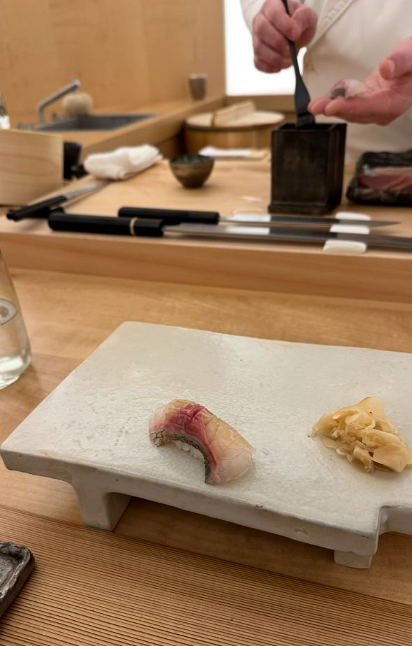 Conciergerie privée Paris, nigiri servi à l'unité sur ardoise blanche dans un restaurant omakase japonais